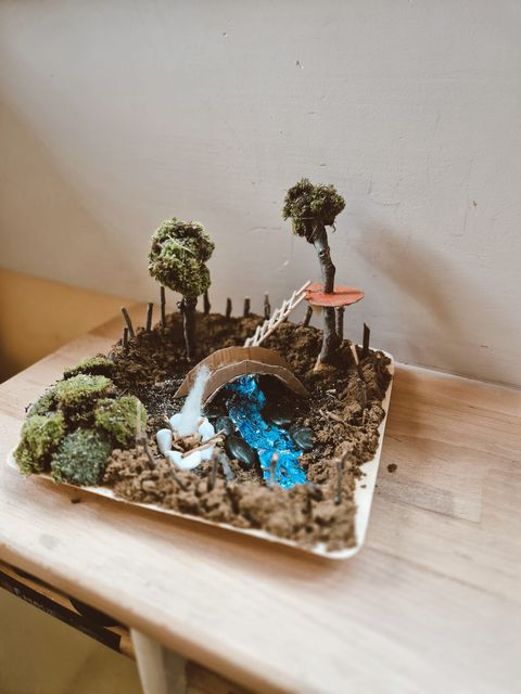 A miniature moss and bridge diorama on a tray